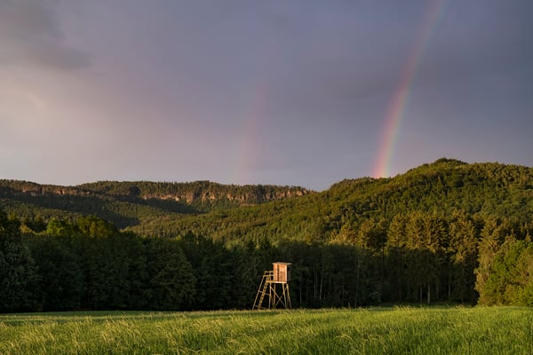 Aufziehende Unwetterfront mit Regenbogenbildung während eines Sonnenaufgangs am Panoramaweg bei Mittelndorf. 