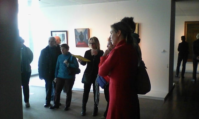 Photo de la guide et d'un groupe de visiteurs lors de la visite des œuvres d’art belge de l’expo Belfius