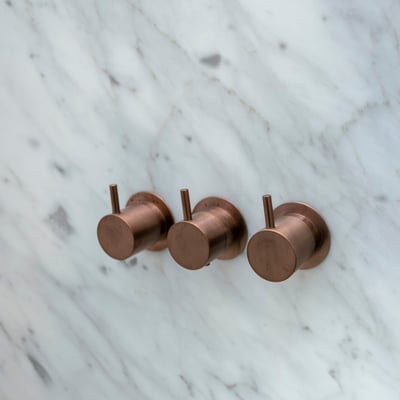 Marmurinėje dušo sienoje įmontuotos čiaupų rankenėlės