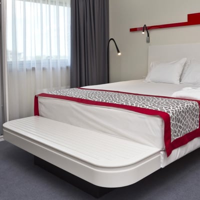 Hotel bed with integrated luggage rack made from white solid surface