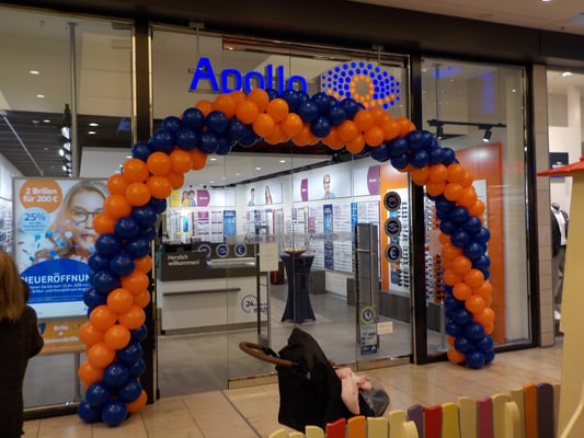 Eingangsbogen. Doppelt spiralförmig gedreht mit Pfeil in der Mitte. Apollo Optik.