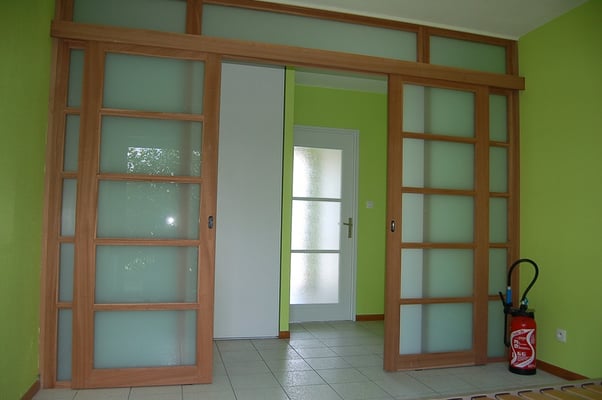 Portes coulissantes dans cloison et imposte vitrées, agrandissant l'espace en conservant la luminosité.