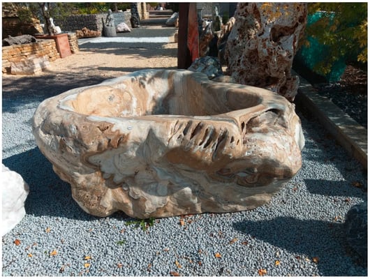 Findlingstrog mit auffälliger Marmorierung als Brunnen/Wasserspiel.