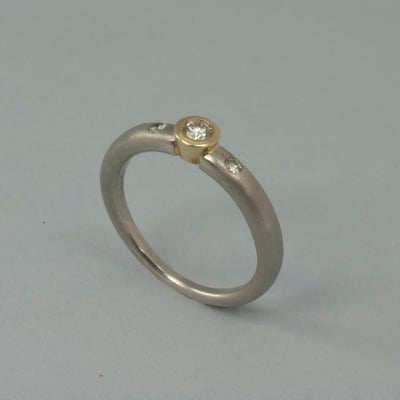 Platinring mit in Gelbgold gefaßtem Brillant und 2 kleinen Brillanten