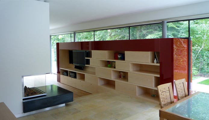 Rote Box: Durch die Glasfassade durchgestecktes Möbelstück. Rot emailliertes ESG-Glas, Holzwerkstoffplatten furniert (Ahorn gebleicht). Offener Heizkamin mit Grundplatte aus gefärbten Beton - Foto © Knauer Architekten