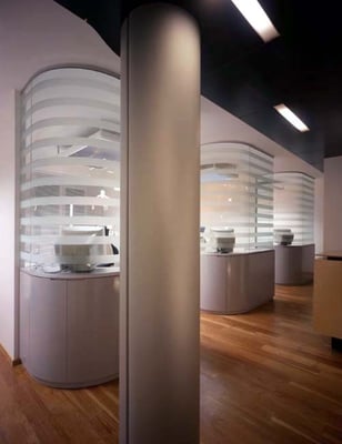 Behandlungsbereiche mit semitransparenten, gebogenen Glaswänden samt Unterschränken.