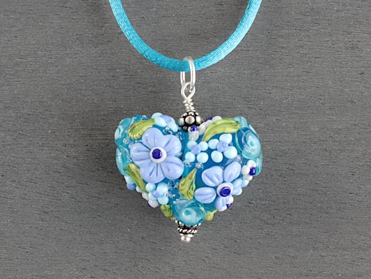 Herzanhänger mit aufgesetzten Blüten in Blautönen