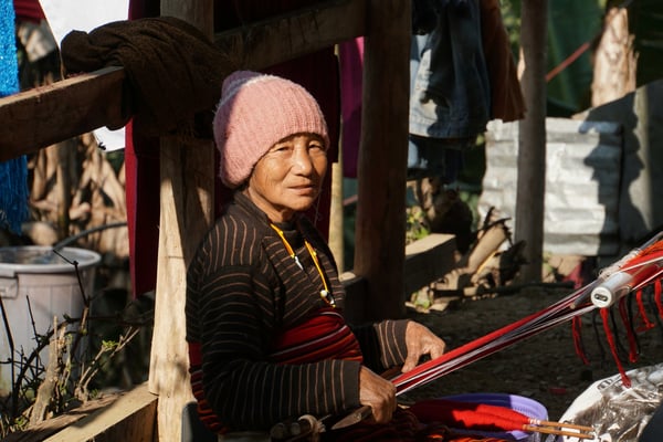 Die Weberin mit dem "Wand-Beckengurt-Webstuhl" - um das Fach zu öffnen, verwendet sie eine Neonröhre...