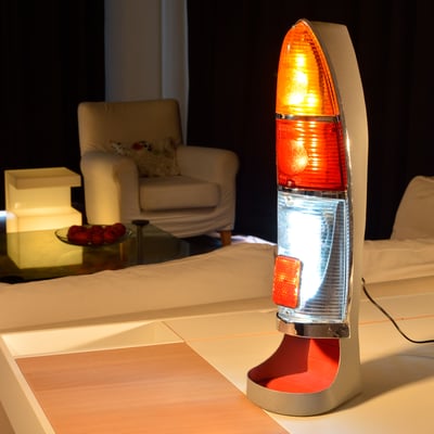 Lampe d'ambiance construite autour d'un feux arrière de Fiat des années 50 chiné en brocante, le bati qui supporte le feux est carrossé sur mesure en tôle acier pliée et soudée