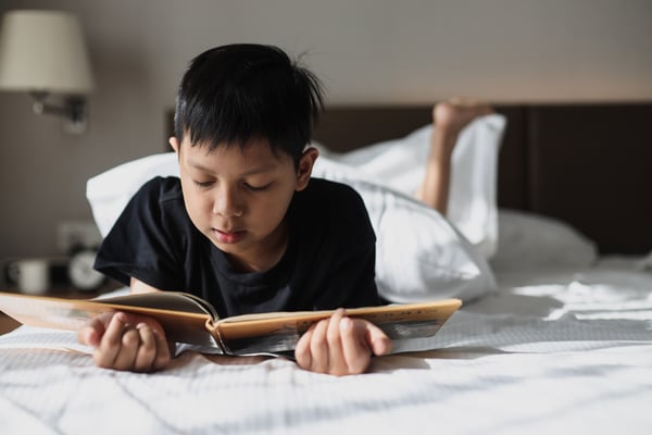 Boy reading book on bed
