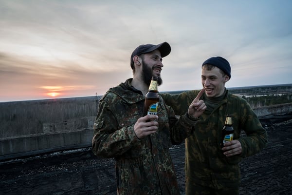 Jimmy and another stalker laughing and drinking beer on the roof of a building in the ghost town of Pripyat.