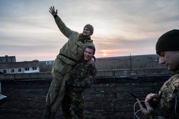 Stalkers having fun during the sunset in a roof of a building of the ghost town of Pripyat