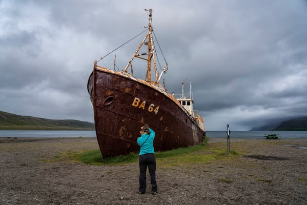 Iceland. A tourist photographs the remains of Garðar BA 64. The ship was built in 1912 as a cutting-edge whaling vessel. After years of faithful service and numerous different owners, it was decommissioned in 1981 and run aground in the Skápadalur Valley