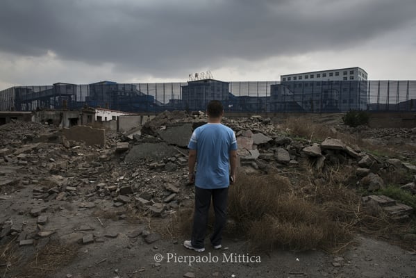 Liang in front of the ruins of his home where he lived before the evacuation of the village of Qiabuqi