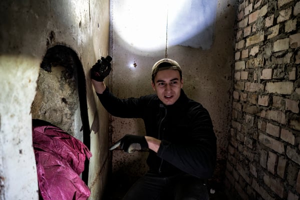 Maxim Vladimirovich, the tour guide, showing tourists how it is possible to enter even illegally into the bunker through this hole