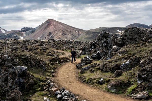 Iceland. A hiker begins the walk through the lava fields, starting from the Landmannalaugar base camp, in a volcanic region featuring coloured mountains and natural hot springs. The area is a popular tourist destination due to its geological formations