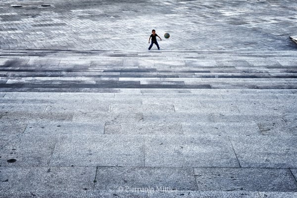 A child playing football in an empty square