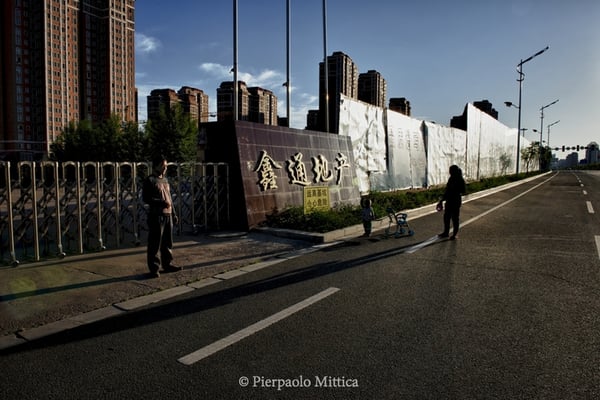 The guardian of some unfinished  buildings with his wife and his son., Along an empty road