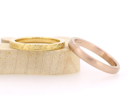 女性用リングはイエローゴールドに月桂樹とミルグレインを、男性用リングはピンクゴールドにヘアライン加工を。