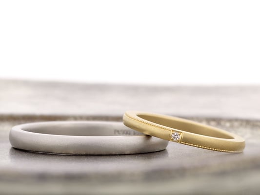 女性用リングはイエローゴールドにミルグレインとダイヤをあしらい、男性用はシンプルなプラチナリングに。どちらも表面はマットな仕上げです。