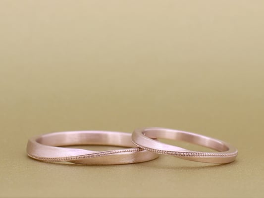 斜めに入ったミルグレインが印象的なリング。どちらもツヤ消しのピンクゴールドに。