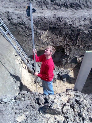 Mit einem Nivelliergerät wird die tiefe der Baugrube ermittelt.