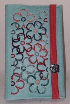 Stickmotiv Blumen in petrol-koralle-lachs-silber auf Filz in pastell-türkis mit kompakter Metallblüte