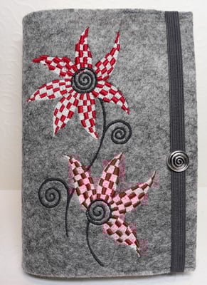 Stickdatei "Schachbrettblume" in rot-weiß-grau auf Filz in hellgrau-meliert, Gummi dunkelgrau, Metalldeko X