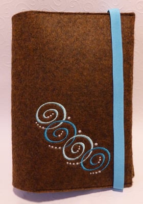 Stickmotiv Spiralkette in türkis und Gummi in türkis auf braun-meliertem Filz