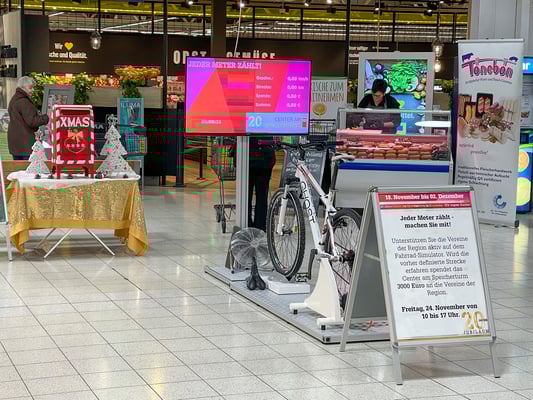Charity.-Aktion mit dem Spendenfahrrad in einem Einkaufszentrum