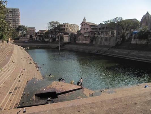 Der Banganga Tank auf dem Malabar Hill. Der Legende zufolge markiert der hölzerne Pfeiler in der Mitte des Wassers den Mittelpunkt der Erde.