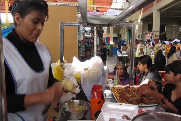 Marktstand mit Frau und knusprig fritiertem Schwein.