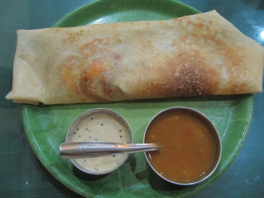 Masala Dosa ist ein knuspriger Reispfannkuchen, gefüllt mit einem würzigen Kartoffelcurry. Dazu gibt's Sambar (einer Soße auf Linsen- und Tamarindenbasis) und Chutney, typischerweise aus Kokosfleisch.