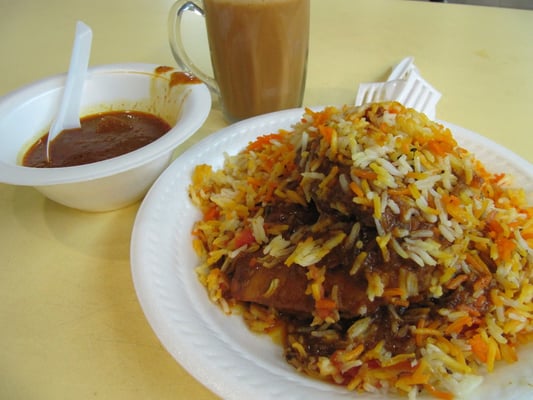 Indisches Briyani mit gegrilltem Hähnchenschenkel, Currysoße und Chai.