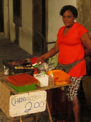 Wurstverkäuferin, die besser grillen als schreiben kann. Das Leben beginnt in Salvador am Abend... und dann wird's feurig wie der Dame ihre Würste und Fleischspieße.