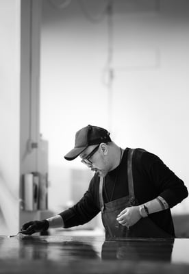 Portret in zwart-wit van kunstenaar James Chiew aan het werk in zijn atelier in Rotterdam door Jordy Leenders.