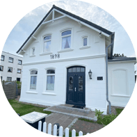 Ein weißes Ferienhaus in Westerland auf Sylt im Bäderstil.