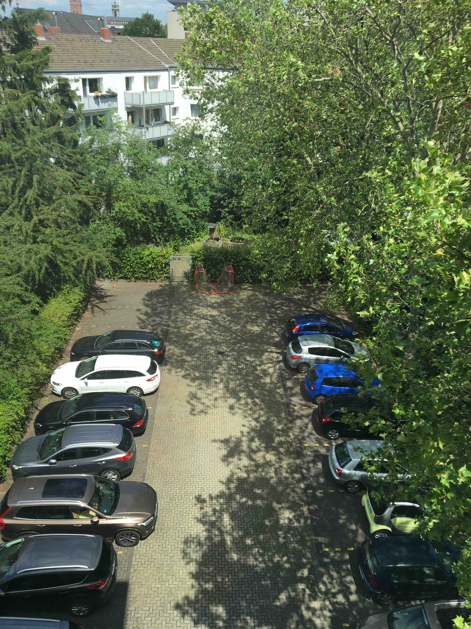 Lehrerparkplatz und der Schulgarten im Hintergrund