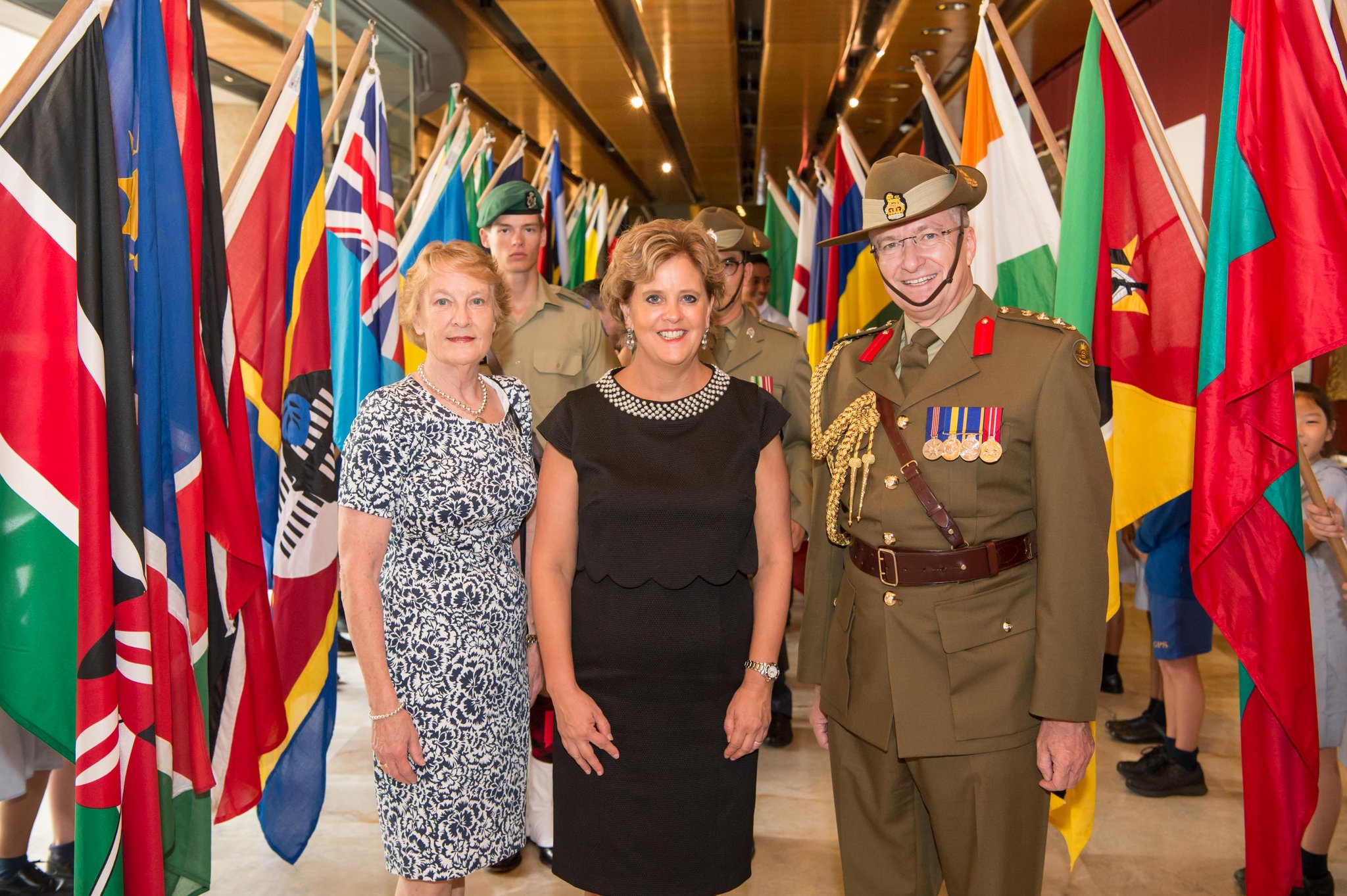 Janet Stewart (left); Her Excellency CMG and Michael Miller RFD with the flags of the 54 Commonwealth of Nations flags