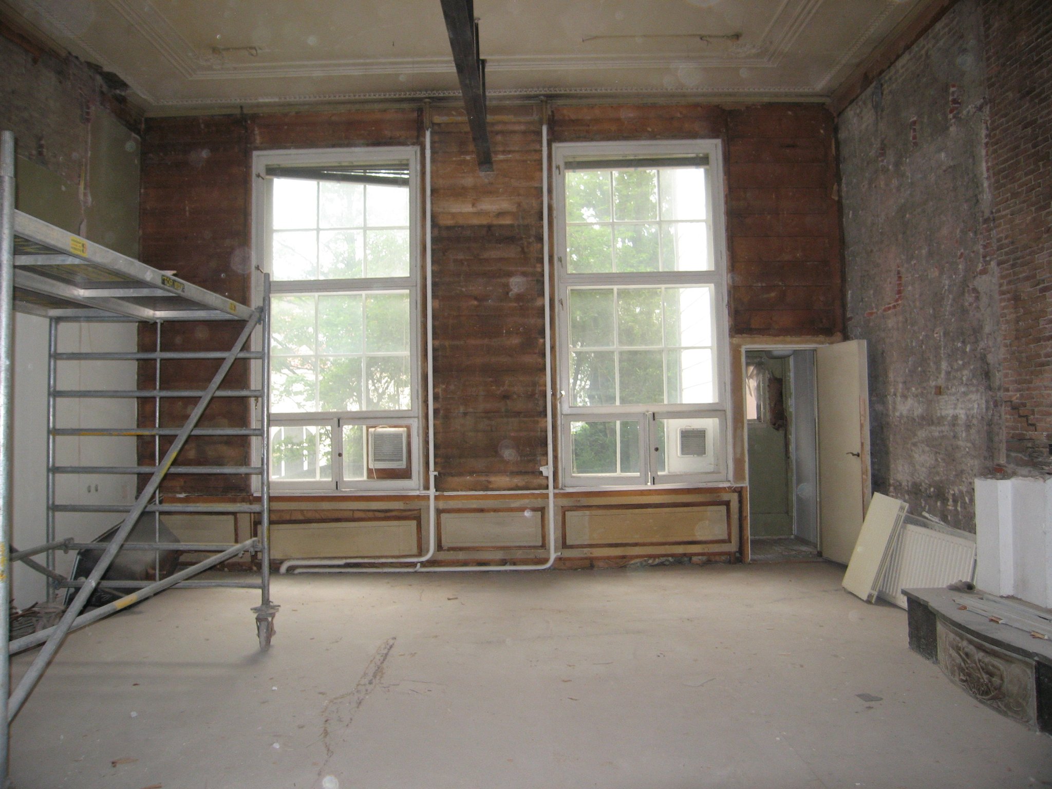 Bouwsporen onder de naoorlogse afwerklaag: 17e-eeuwse wandbetimmering en lambrisering in de achterkamer. 