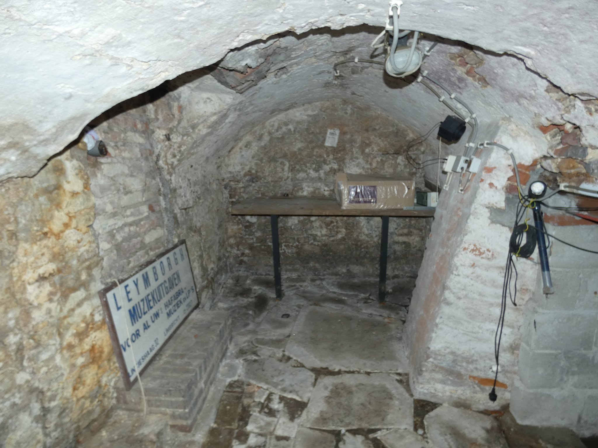 Noordelijke kelder met mergelstenen muren en bakstenen ton. Links een doorgang naar een voormalige kelder.
