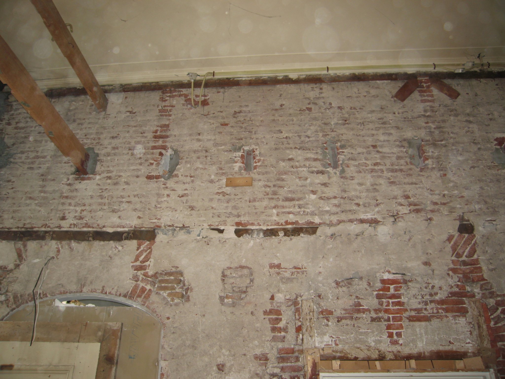 Bouwsporen onder de naoorlogse afwerklaag: balk, horende bij de insteek boven de entree; korfboog. 