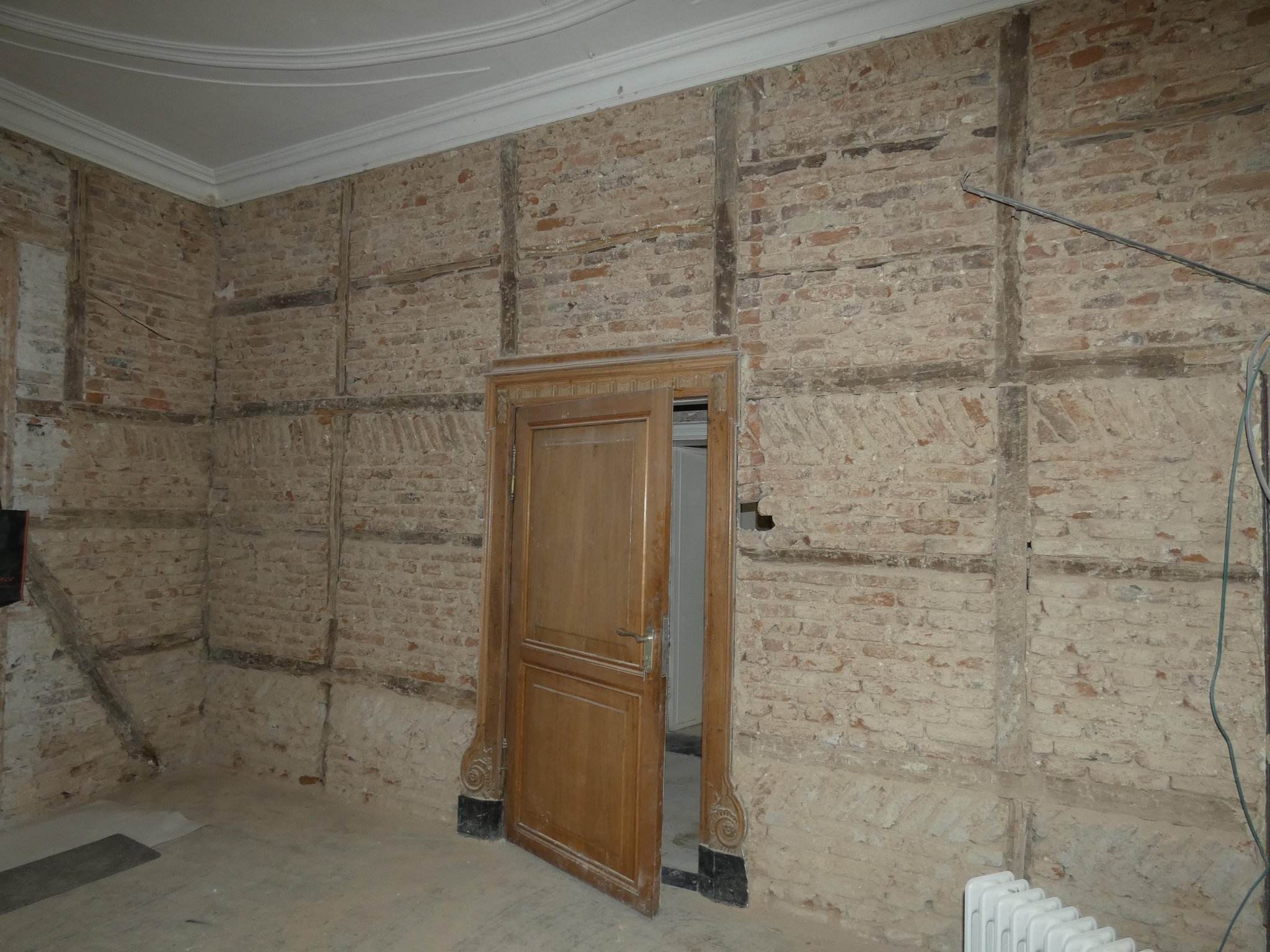 Oorspronkelijke vakwerk wandopbouw tussen de gang en de grote salon: eikenhouten frame met klein formaat veldbrandsteen (waalformaat). 