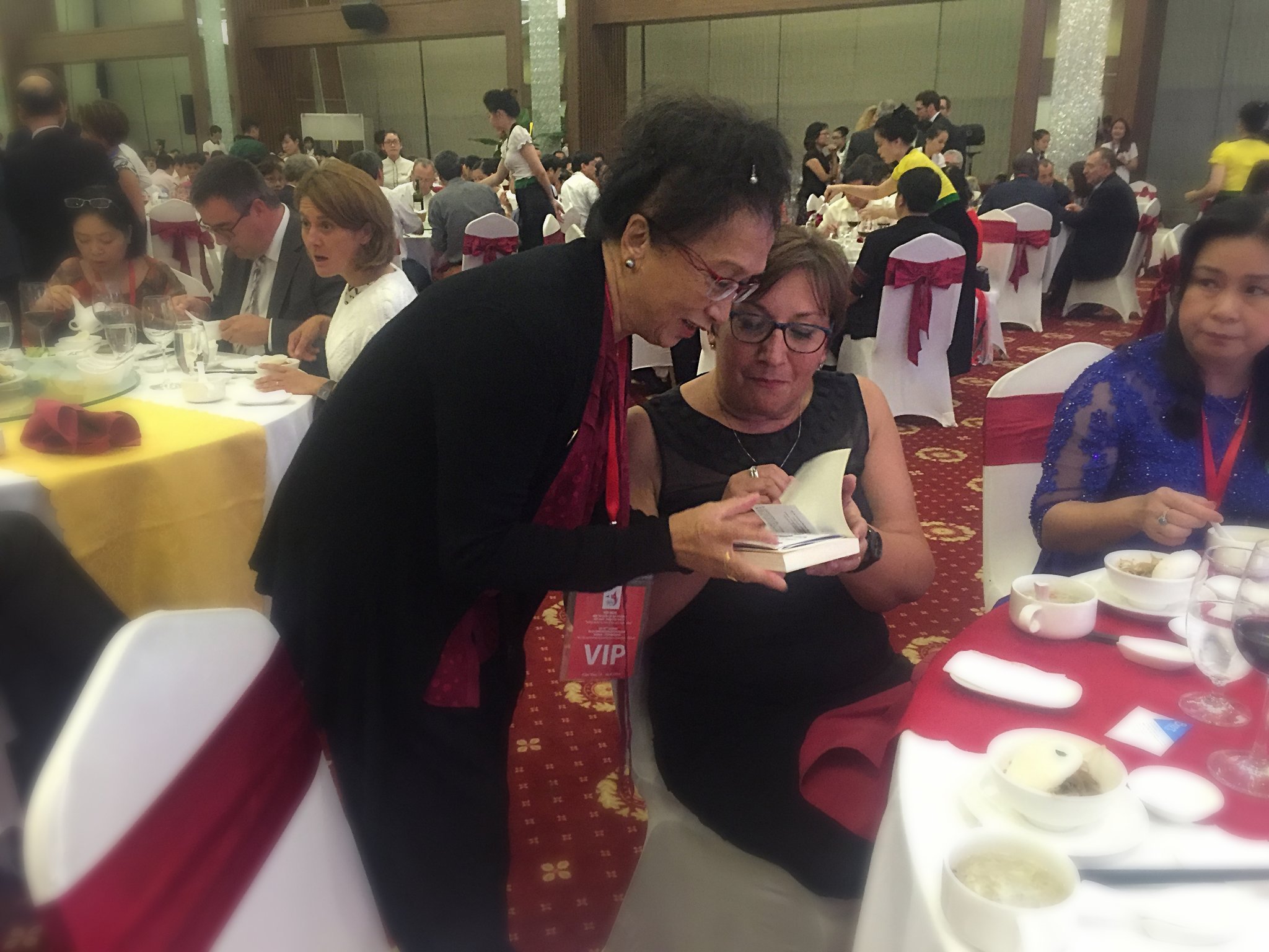 Mme Pinville, Secrétaire d’État auprès du ministre de l'Économie et des Finances, est ravie du cadeau offert par Anna : le livre de Mohed Altrad