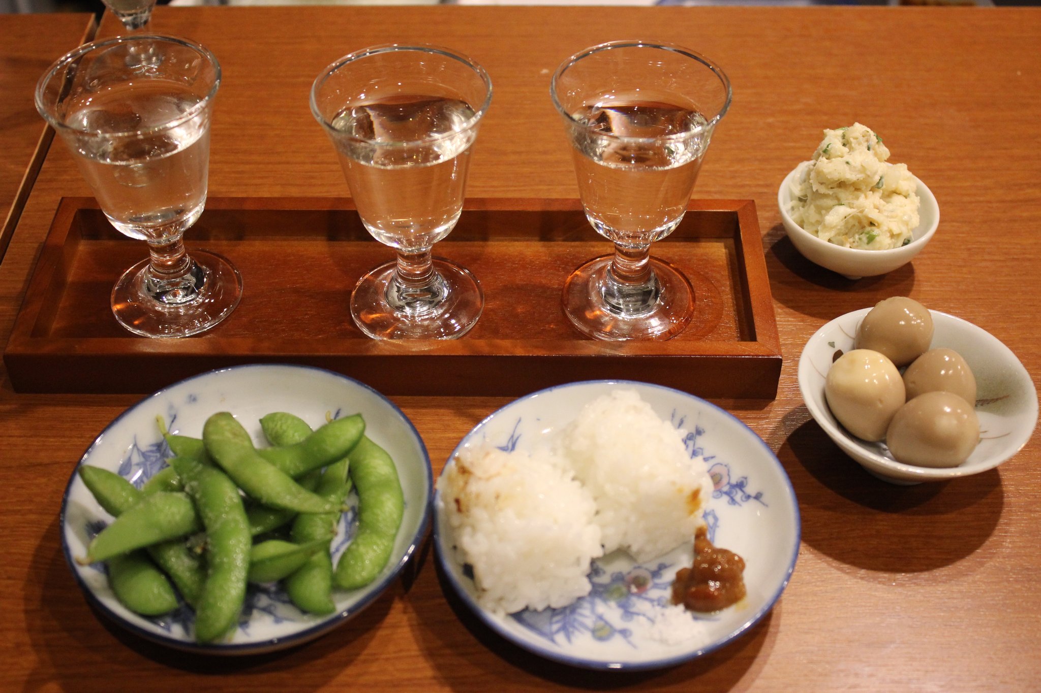 おすすめの「のみくらべおちょこセット」+枝豆です。おにぎりの1つは酒米です。