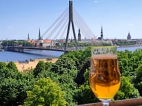 Glass of beer with Riga skyline in background across Daugava River