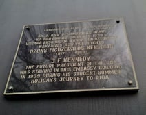 Black plaque with gold lettering at Hotel A22, Riga, indicating that John F. Kennedy stayed in the building on a trip to Latvia in 1939