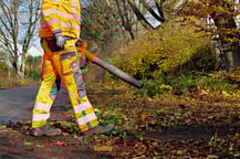 Mitarbeiter mit Laubgebläse im Herbst