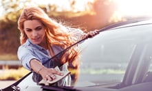 Frau wischt Windschutzscheibe von PKW ab