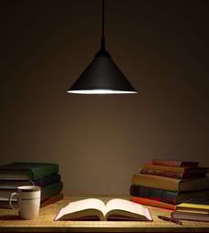 Foto von Bücher am Tisch, beleuchtet von einer Hängelampe